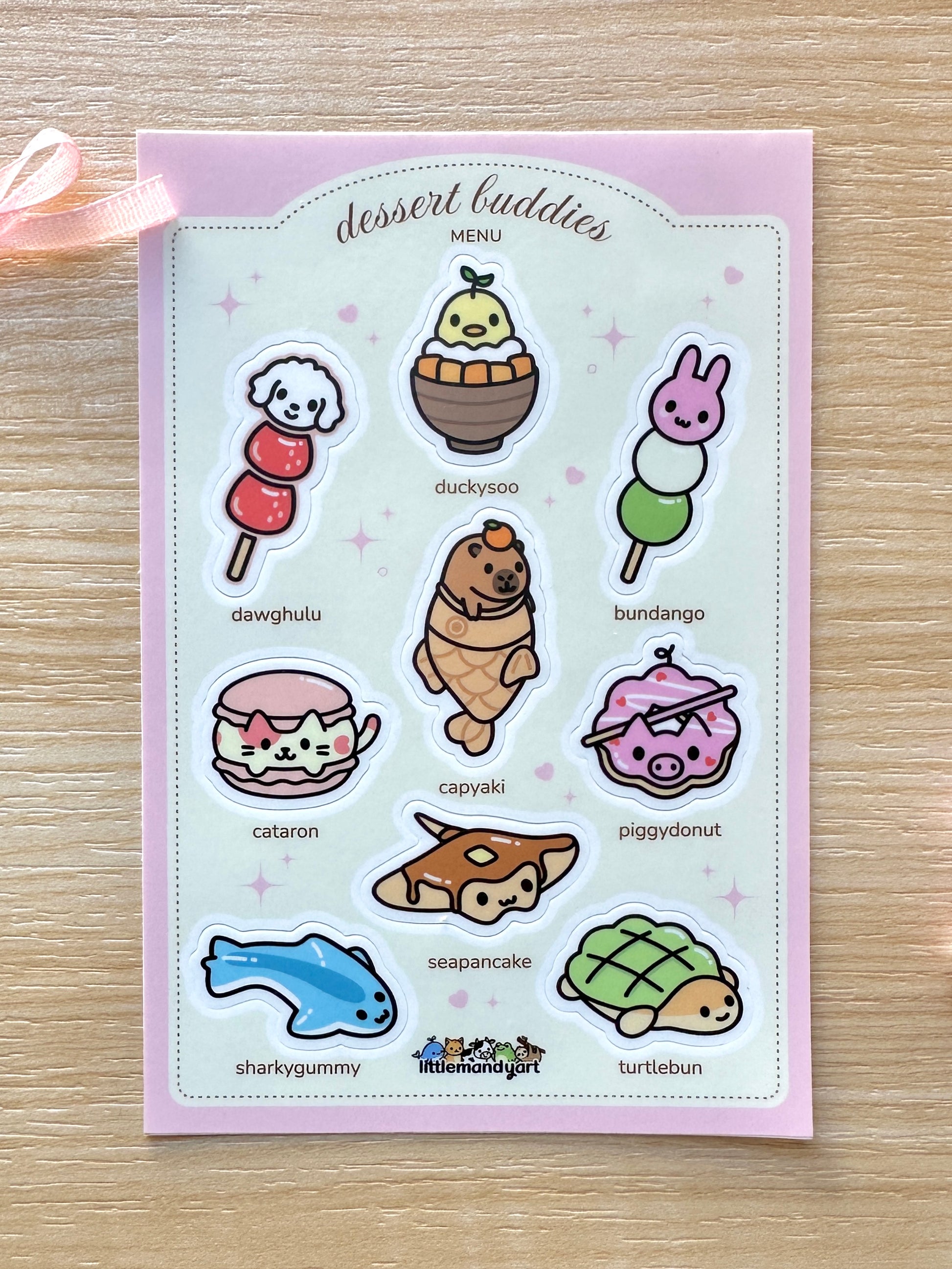 Sticker sheet with cute food-themed characters on a pink background. Featuring Dawghulu, Duckysoo, Bundango, Cataron, Capyaki, Piggydonut, Seapancake, Sharkygummy, and Turtlebun.